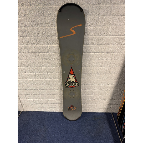 Komplettes Flow Rhythm Snowboard in Grau mit orangefarbener Wellenlinie oben, Flow-Logo und 152, mit Schutzkappe an der Spitze, vor einer weißen Backsteinwand